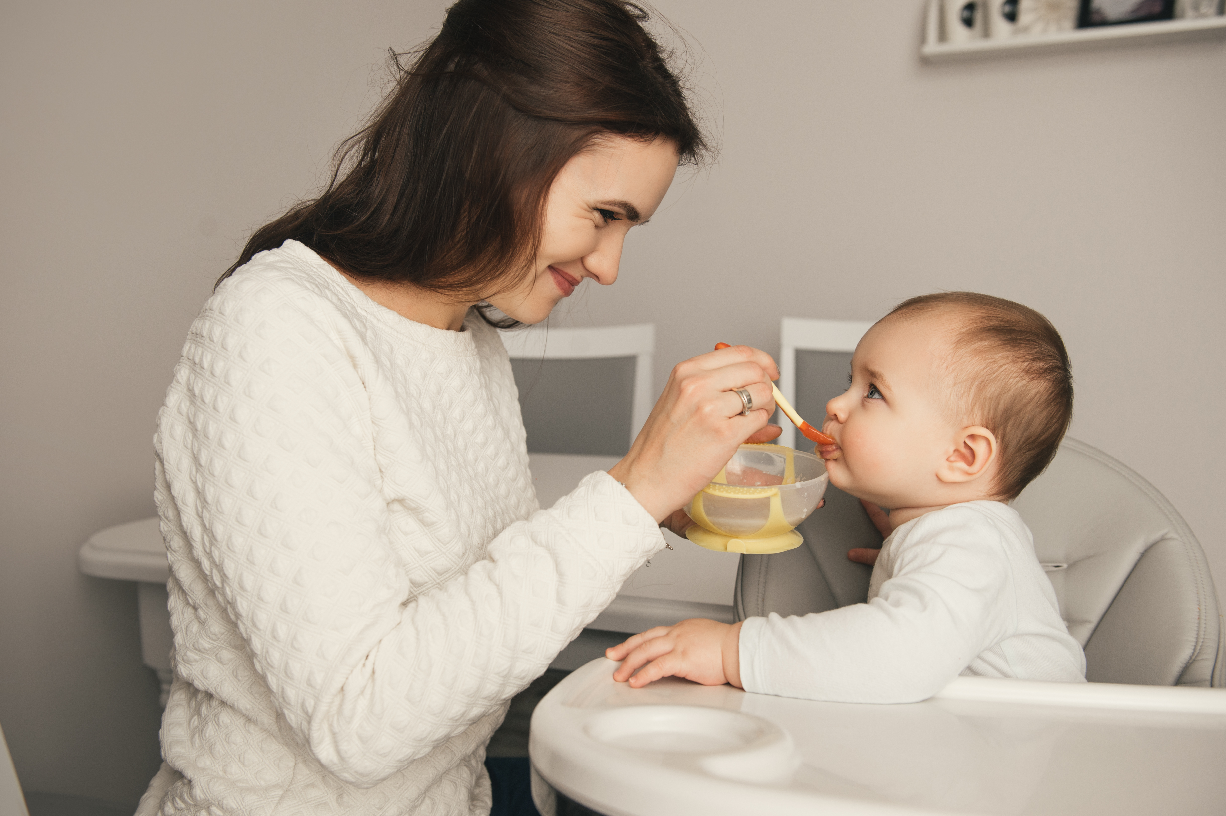 vrouw geeft baby een hapje